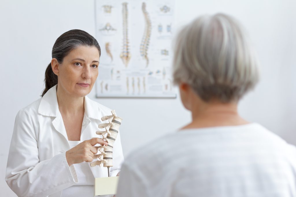 Orthopädin im Gespräch mit einer Patienten zur Analyse der Wirbelsäule.