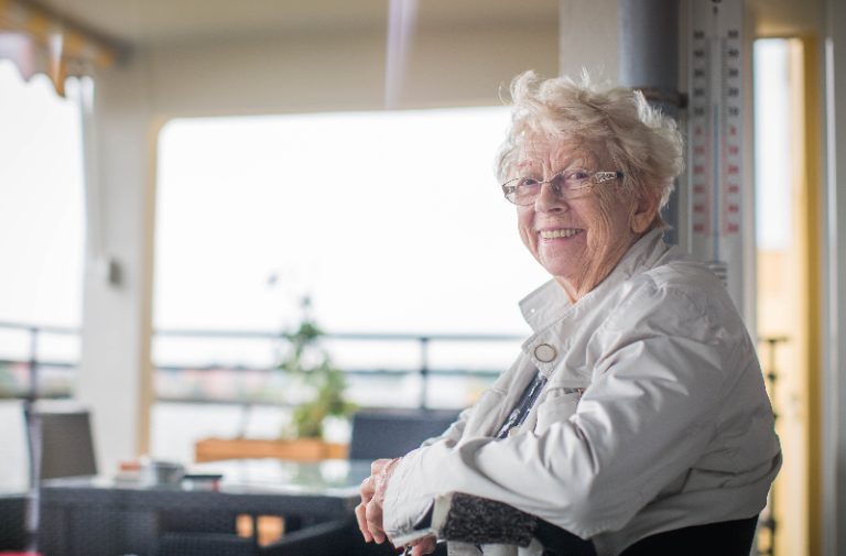 Rosemarie John sitzt im Rollstuhl im Pflegeheim und lächelt.
