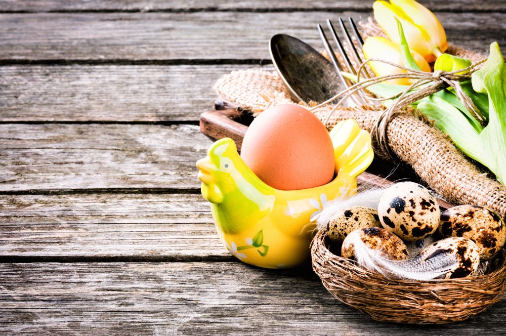 Osterei und Wachteleier sind eingedeckt mit Besteck auf Ostertisch.