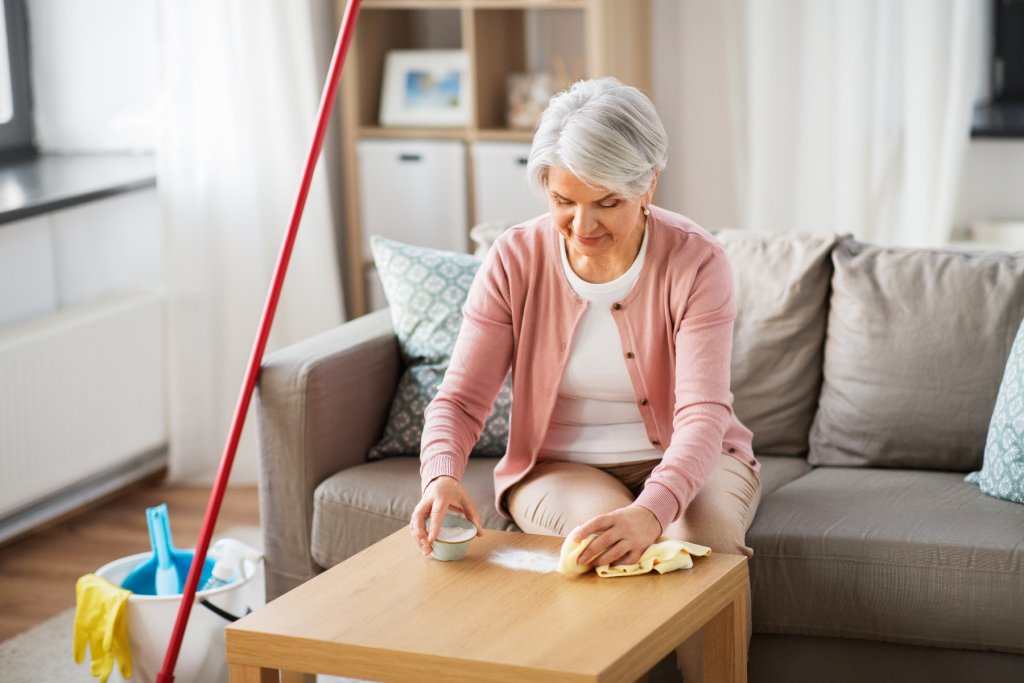 Seniorin sitzt am Tisch mit Hausmitteln für die Reingigung.