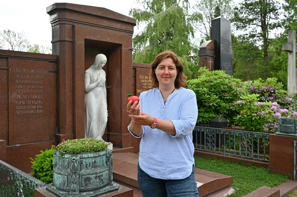 Leckereien am Grab: Verwaltungsleiterin Beatrice Teichmann (46) mit dem Tell-Apfel aus Schokolade an der Ruhestätte seines Erfinders Heinrich Vogel (1844-1911). Foto: Petra Hornig