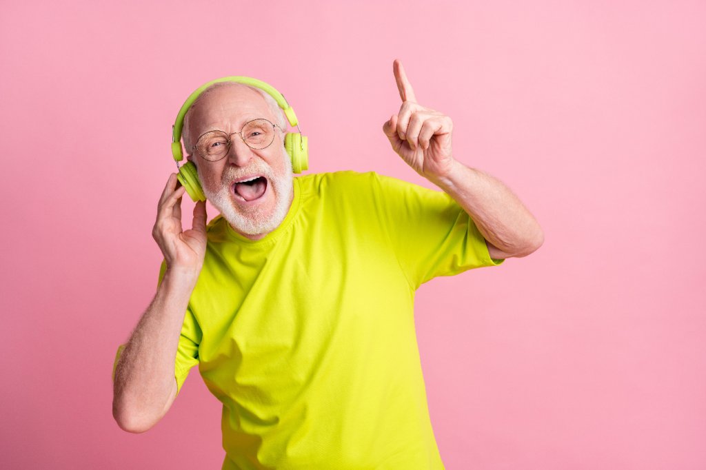 Senior hört mit Kopfhörern Musik und ist in guter Stimmung