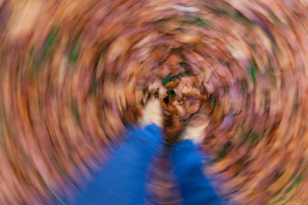 Blick auf die Füße im Herbstlaub mit Schwindelgefühl.