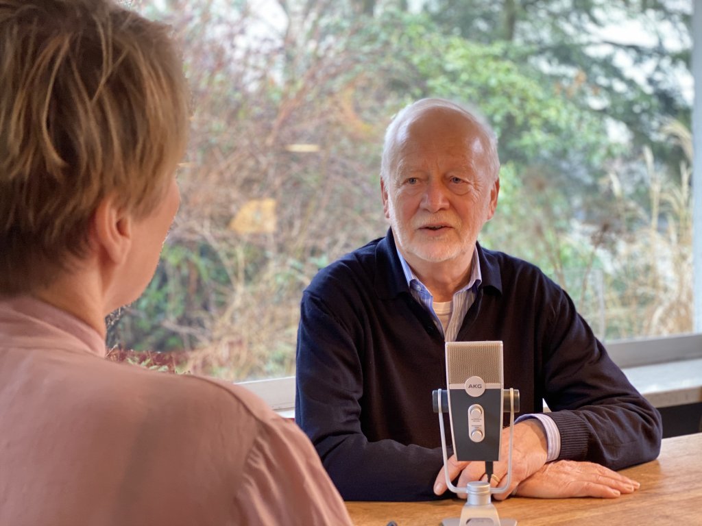 Senior sitzt vor Mikrofon im Gespräch.