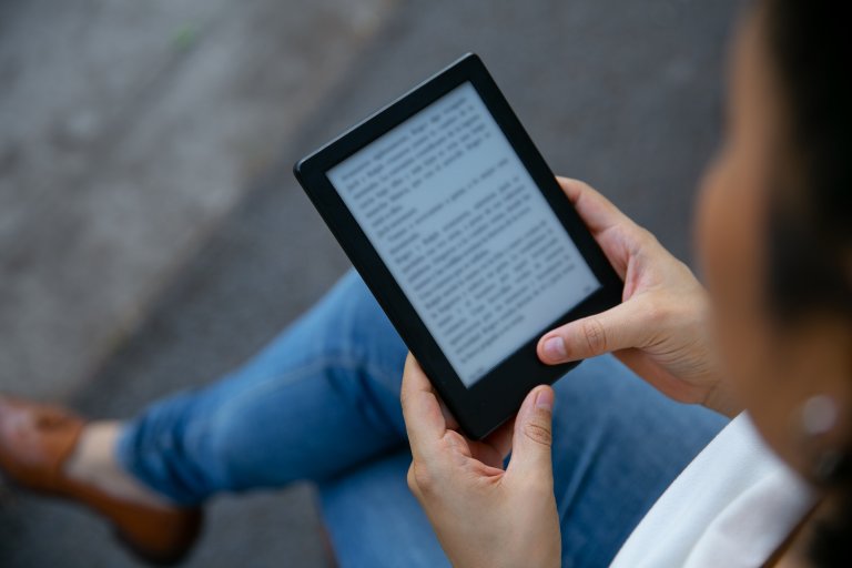 Junge Frau liest auf einem Tablet ein E-Book.