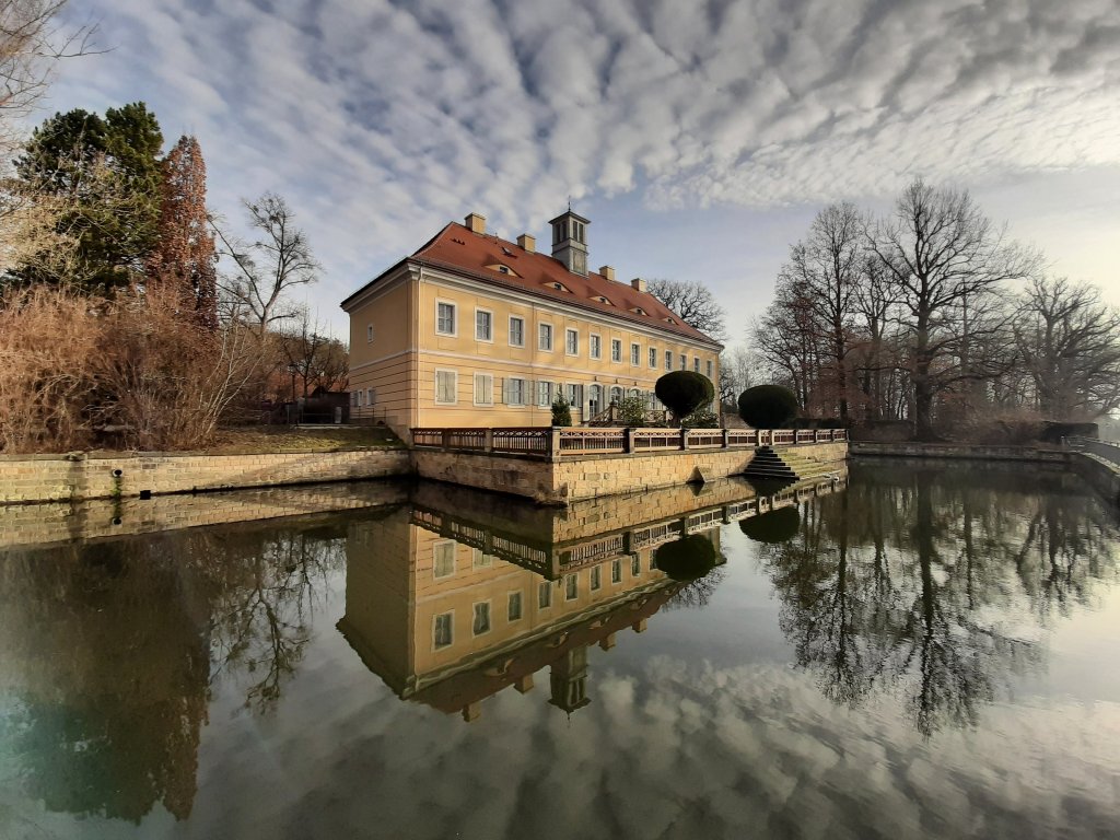 Das Jagdschloss Graupa spiegelt sich im See.