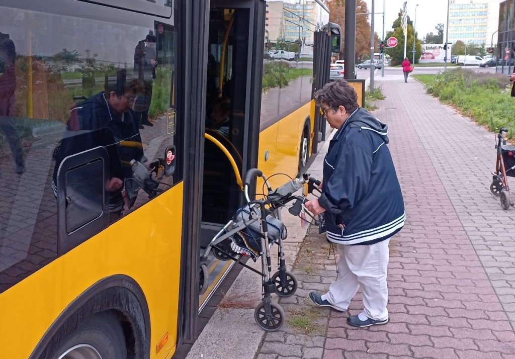 Frau steigt mit Rollator in Bus