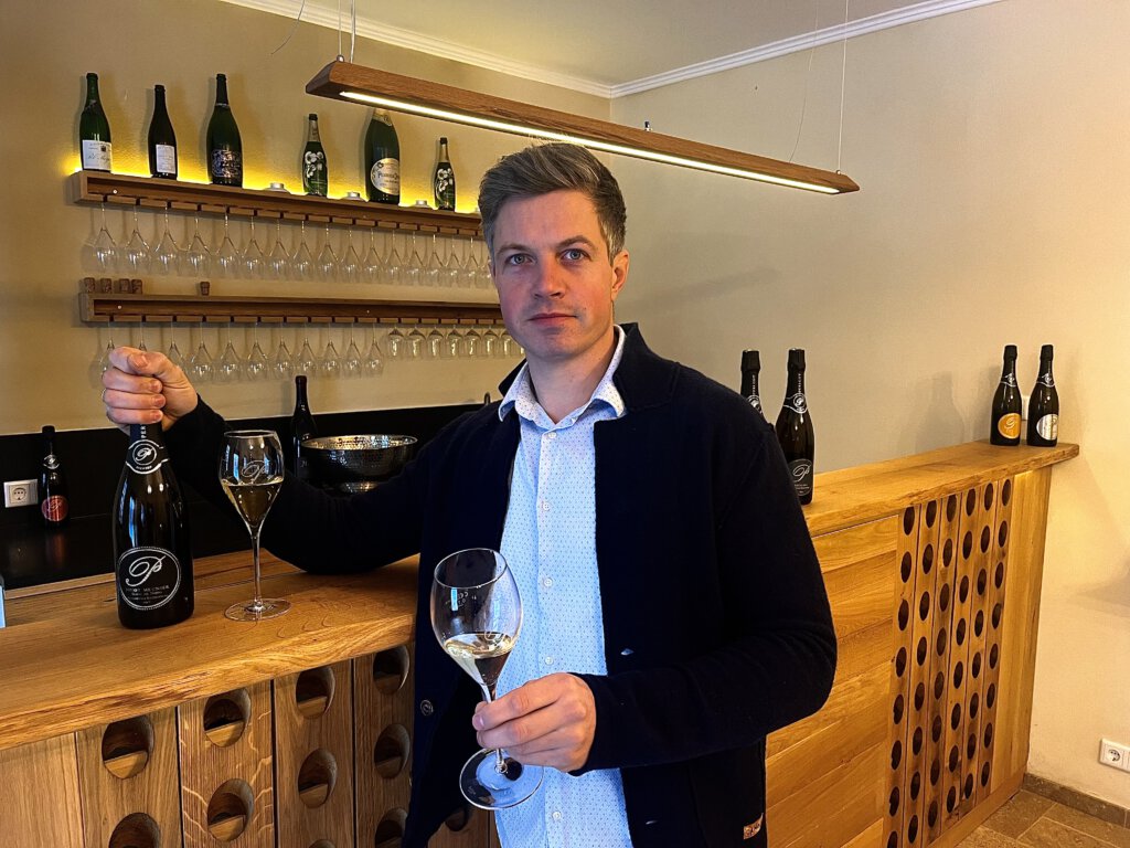 Winzer Hendrik Weber hält Sekt in der Hand.